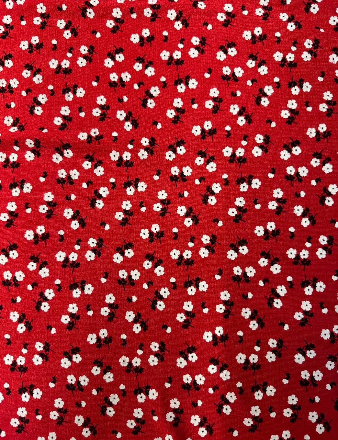 Pattern of small white flowers with black centers on a red background