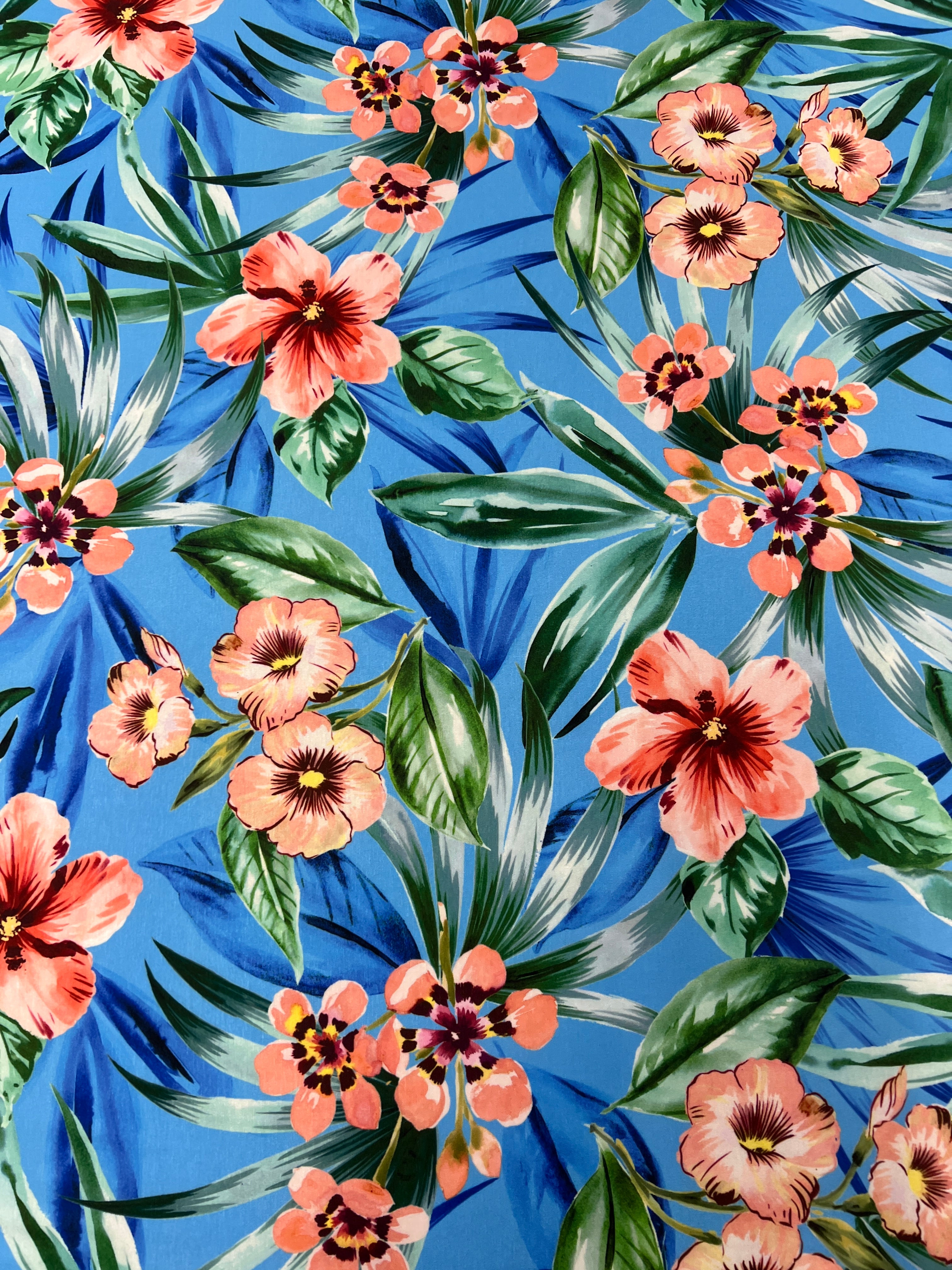 Tropical floral pattern with pink flowers and green leaves on a blue background
