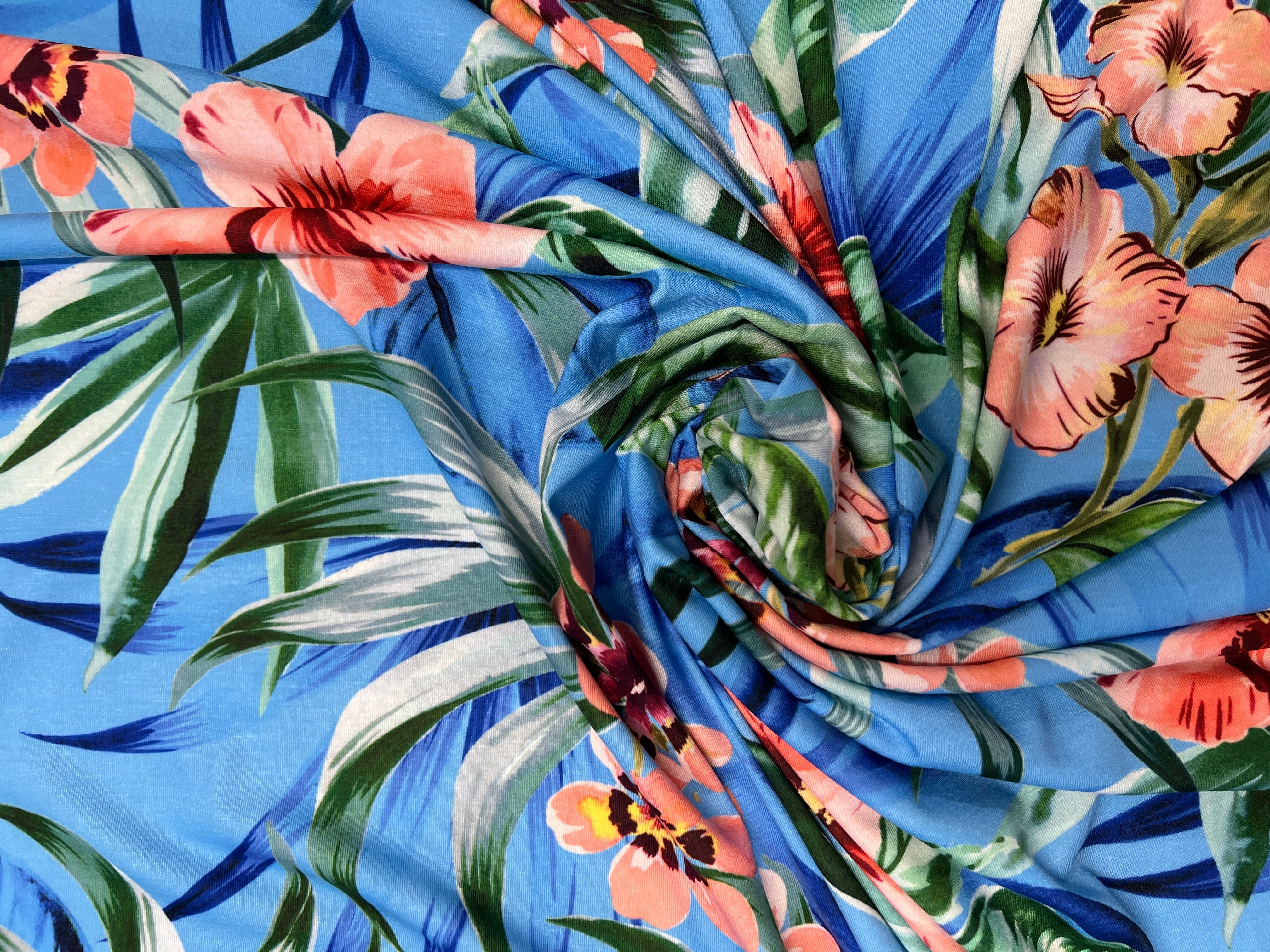 Close-up of fabric with tropical floral and leaf pattern on a blue background