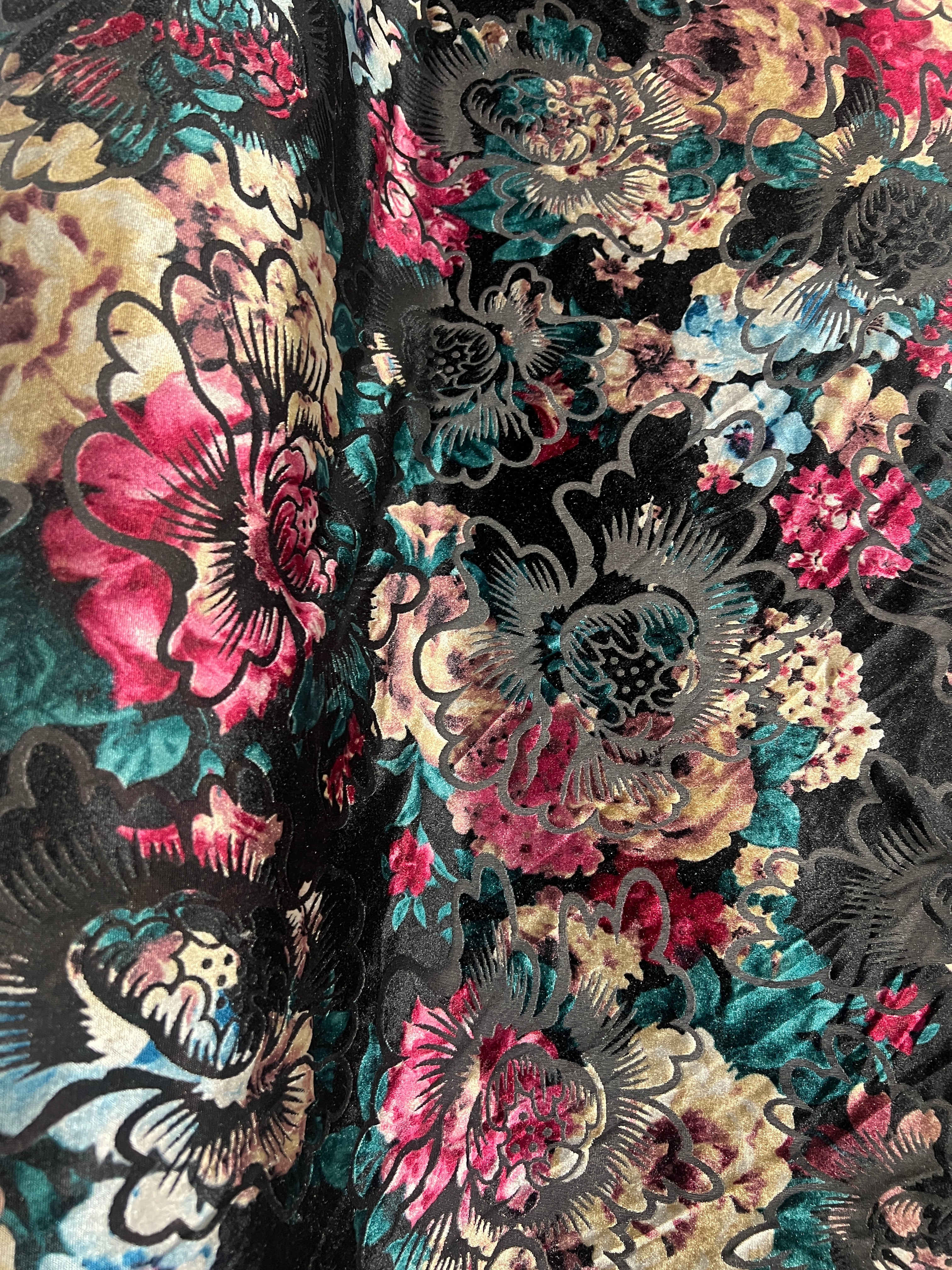 Close-up of floral and butterfly pattern fabric with black, pink, and green colors.