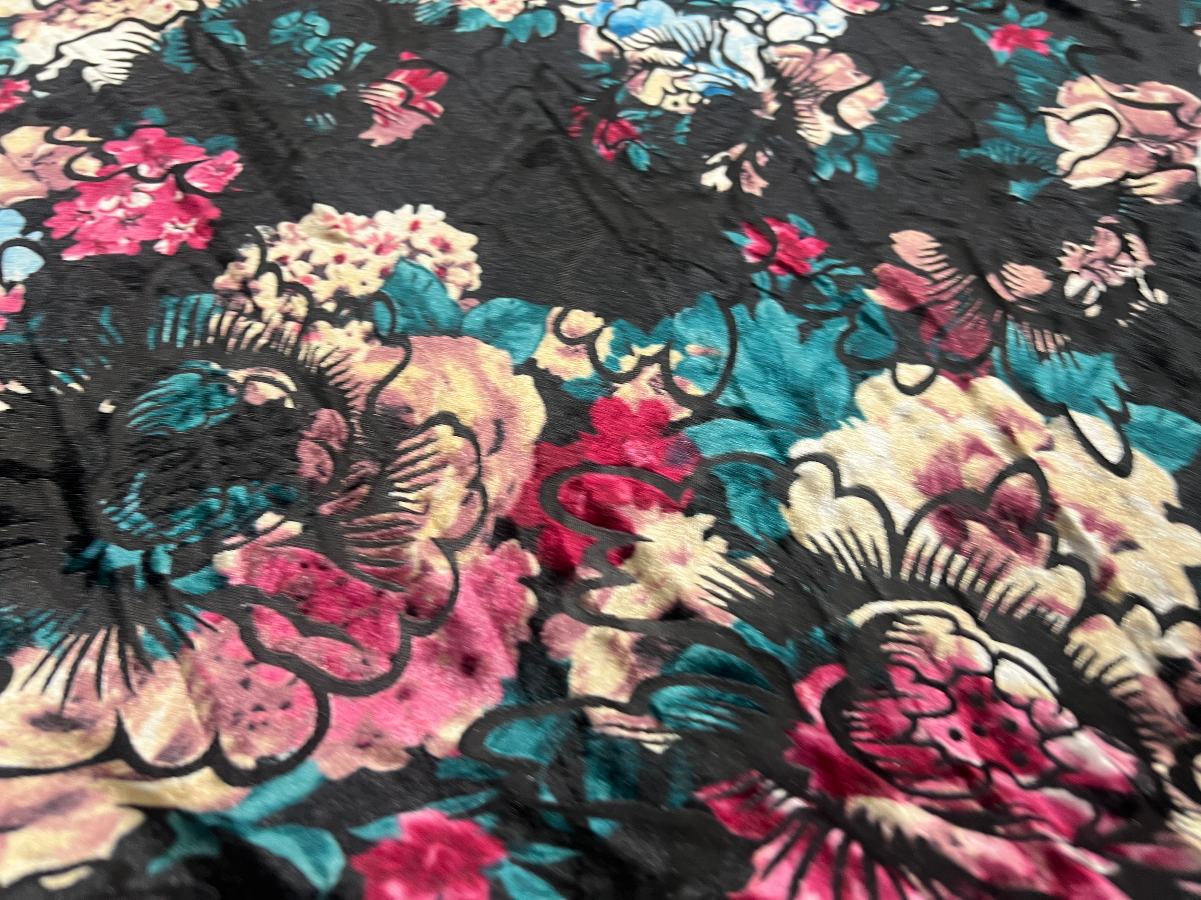Close-up of floral fabric with pink, blue, and black colors.