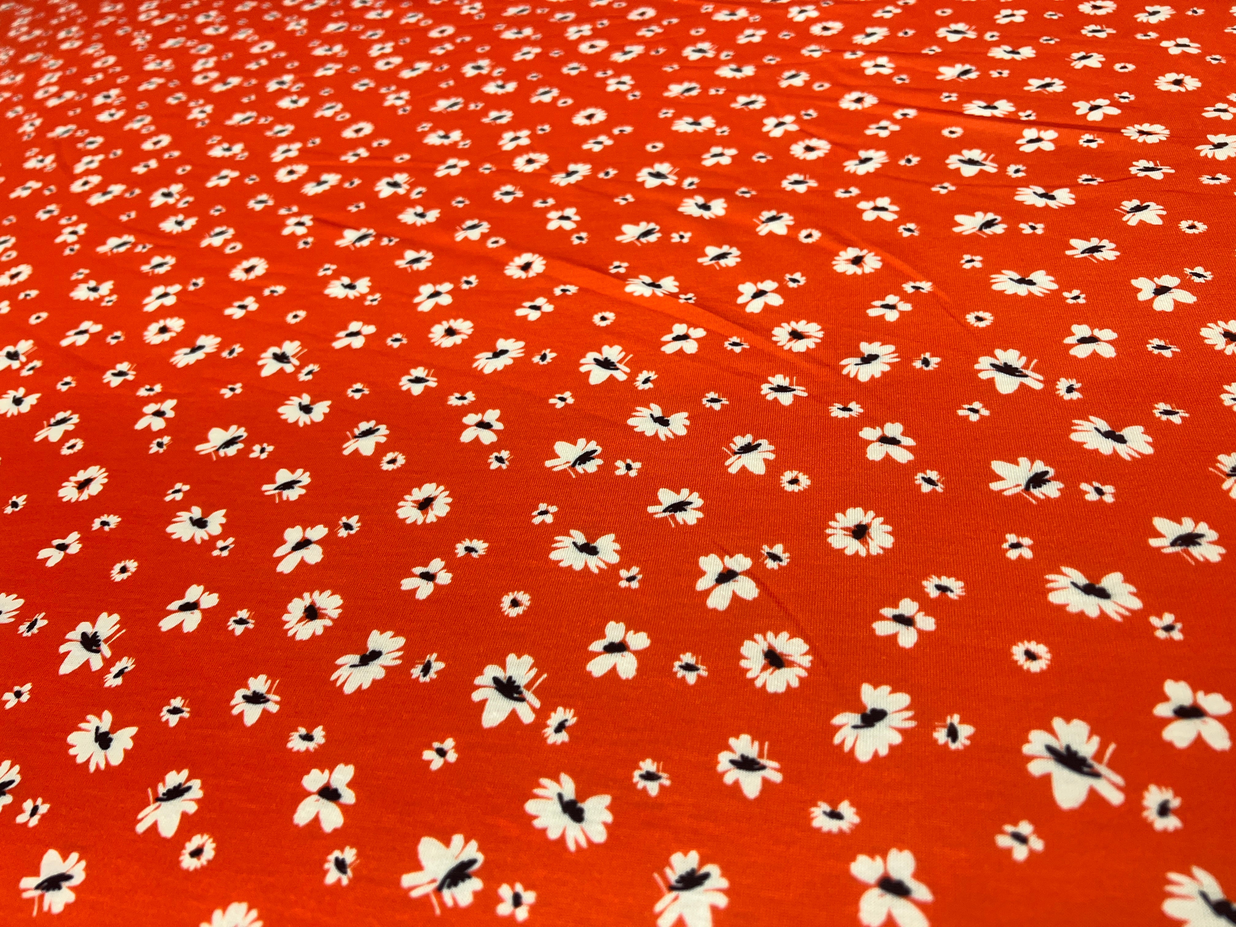 Pattern of small white flowers with black centers on a red background