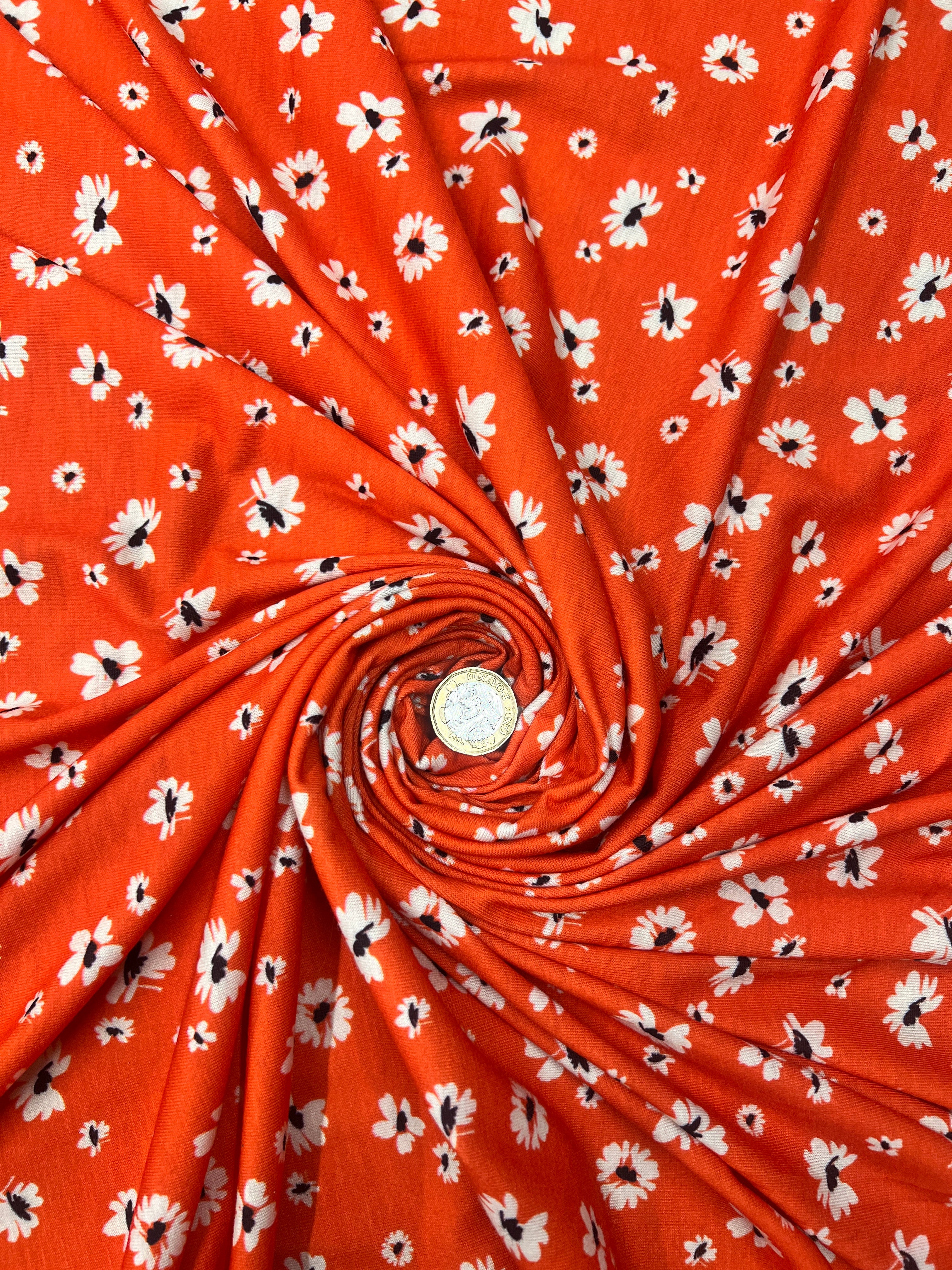 Roll of red fabric with white floral pattern