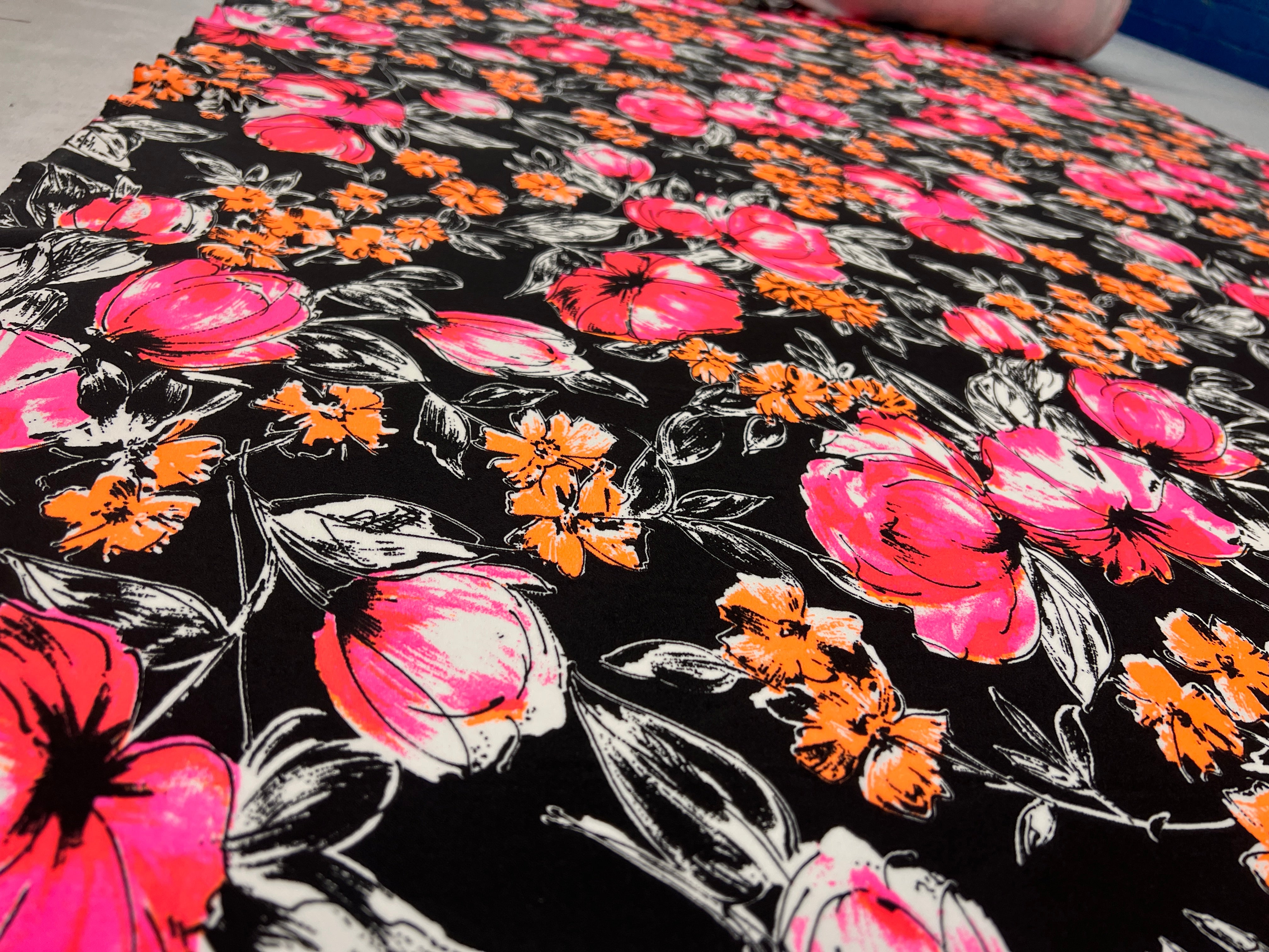 Close-up of floral fabric with pink, orange, and white flowers on a black background