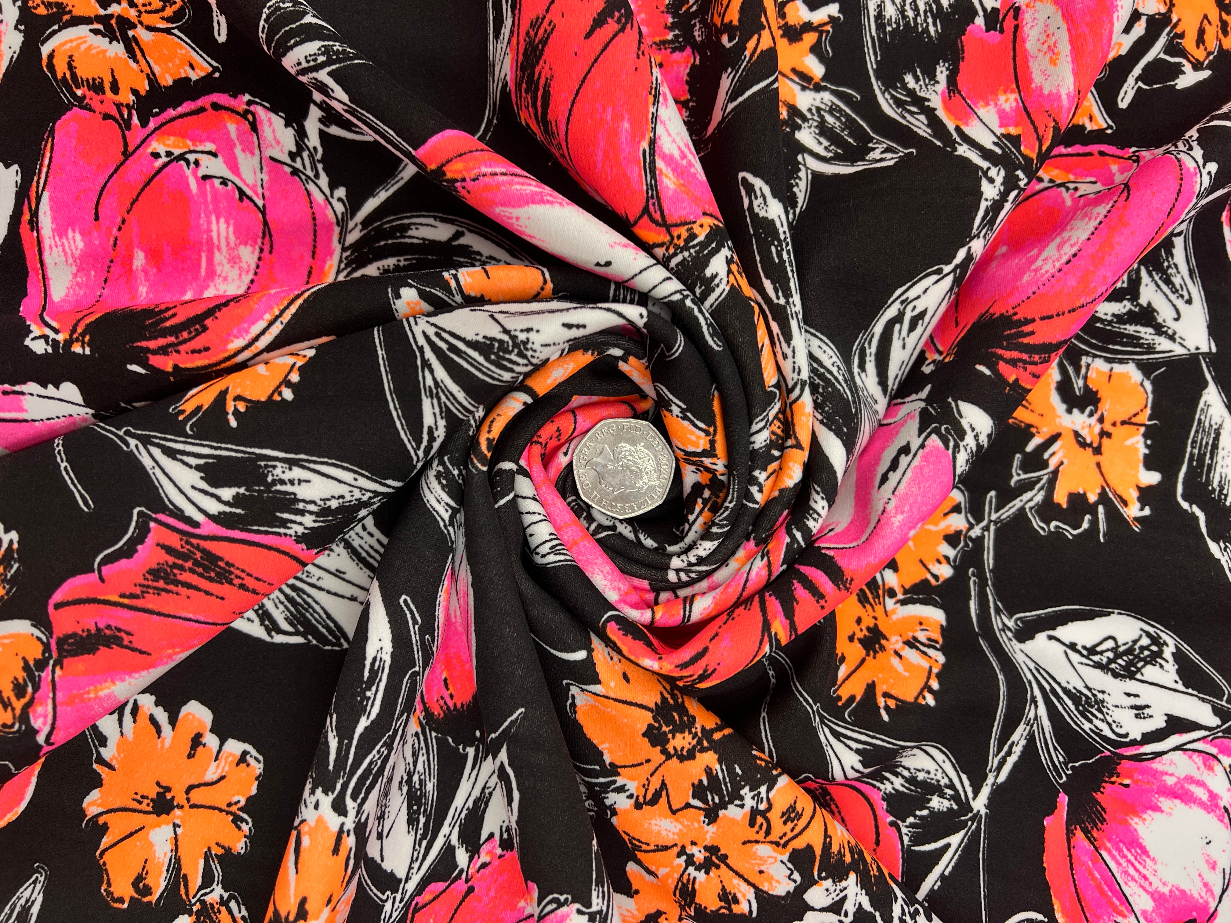 Close-up of floral fabric with pink, orange, and black flowers on a black background.