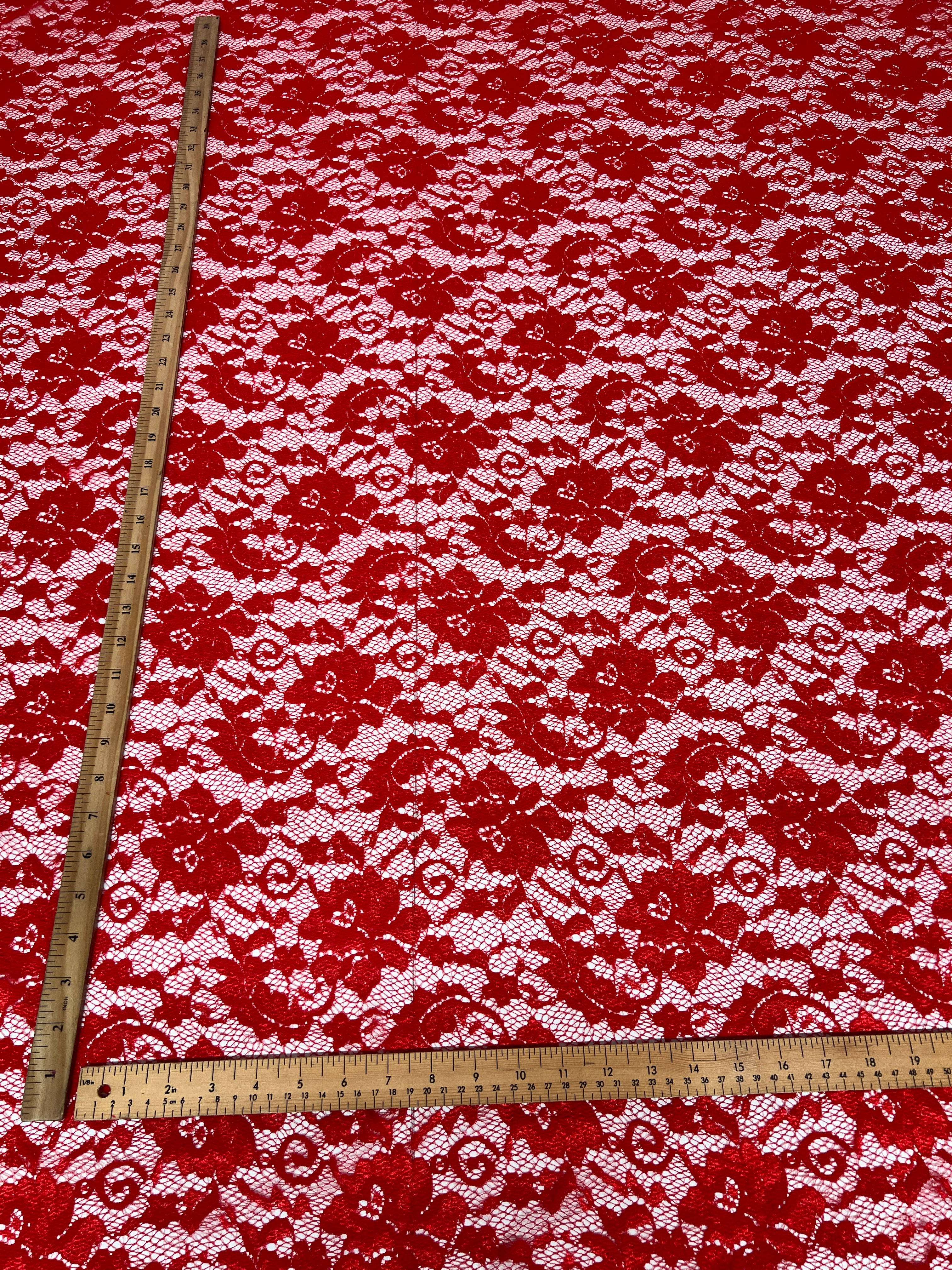 Red and white floral lace fabric with a ruler for scale
