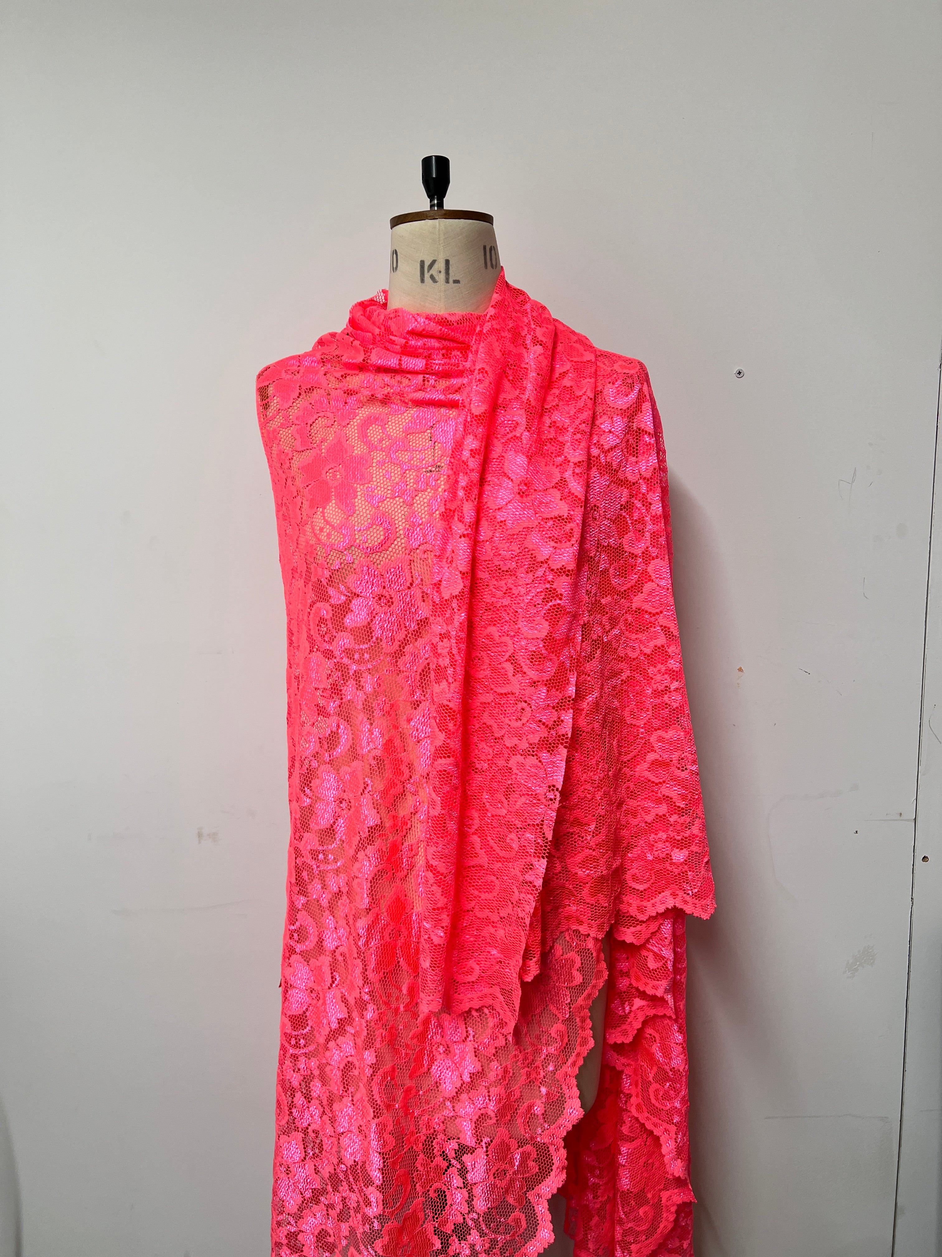 Pink lace dress on a mannequin against a white background