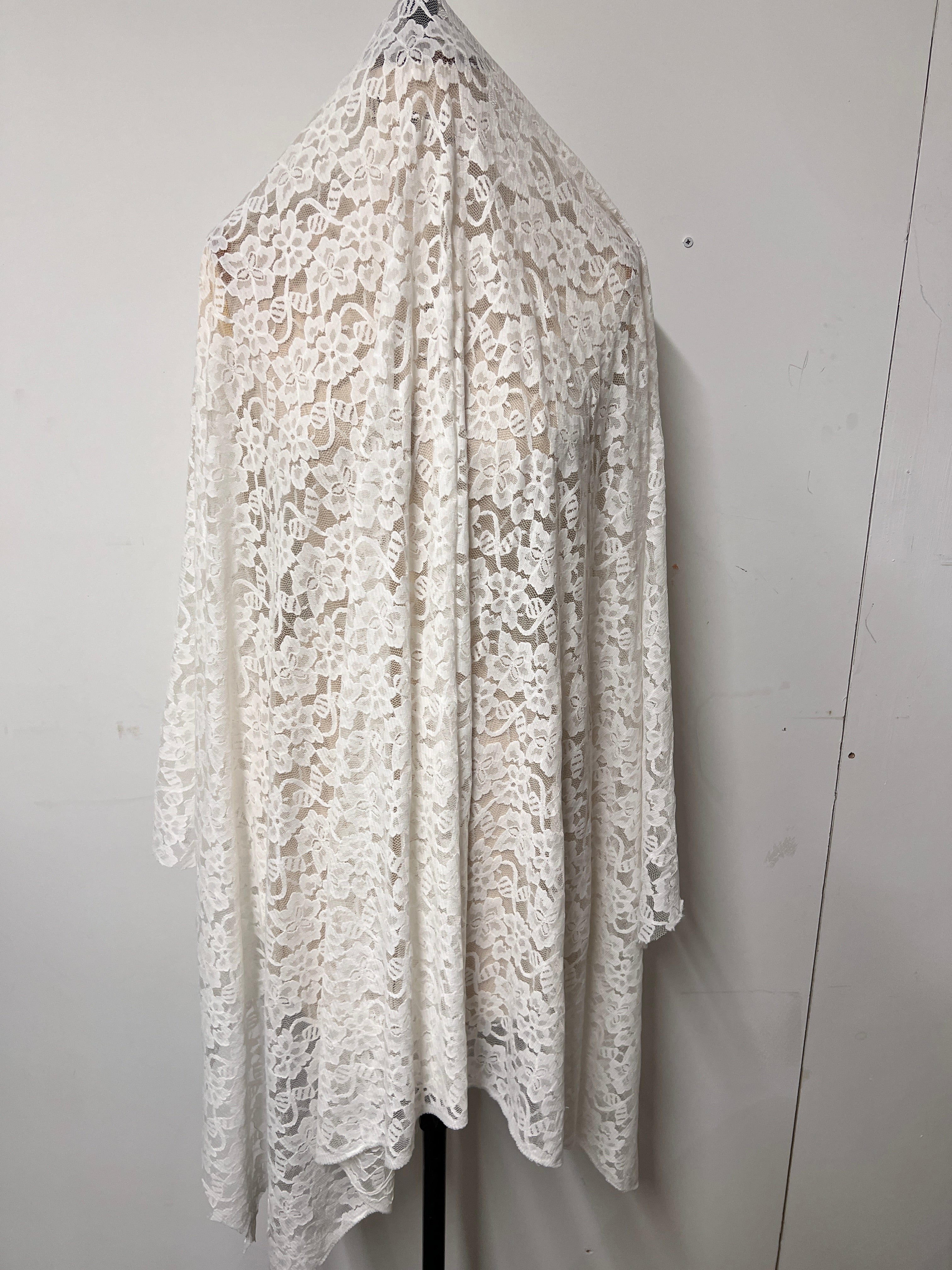 Roll of white lace fabric on a light gray background