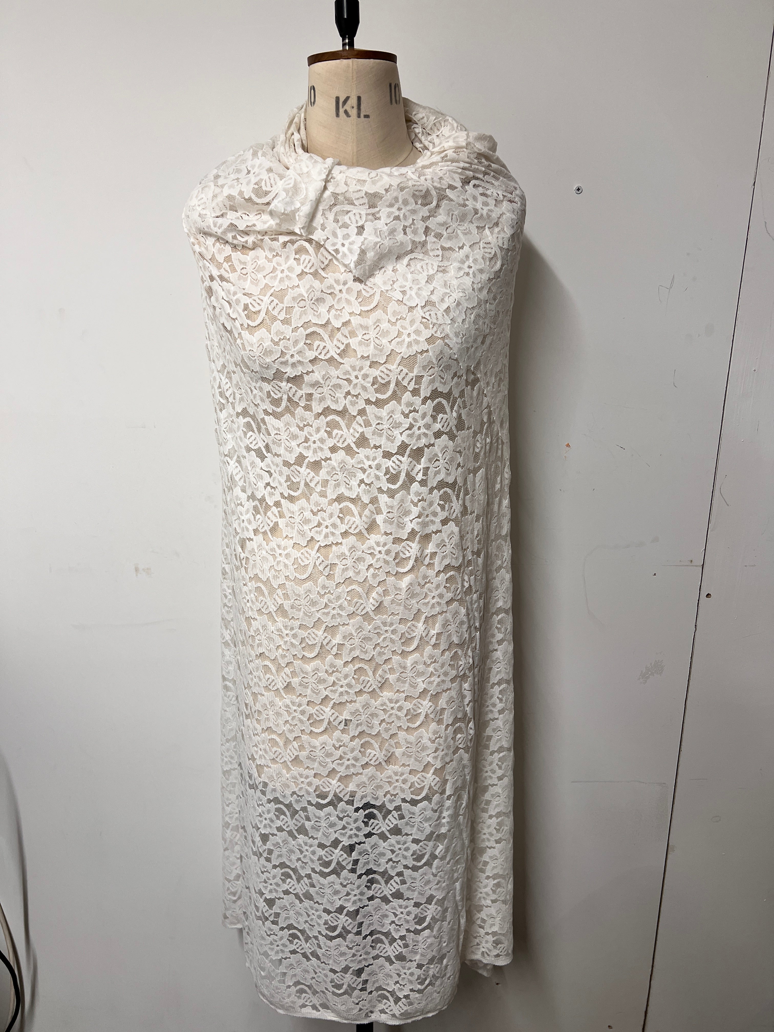 Roll of white lace fabric on a mannequin torso against a white background