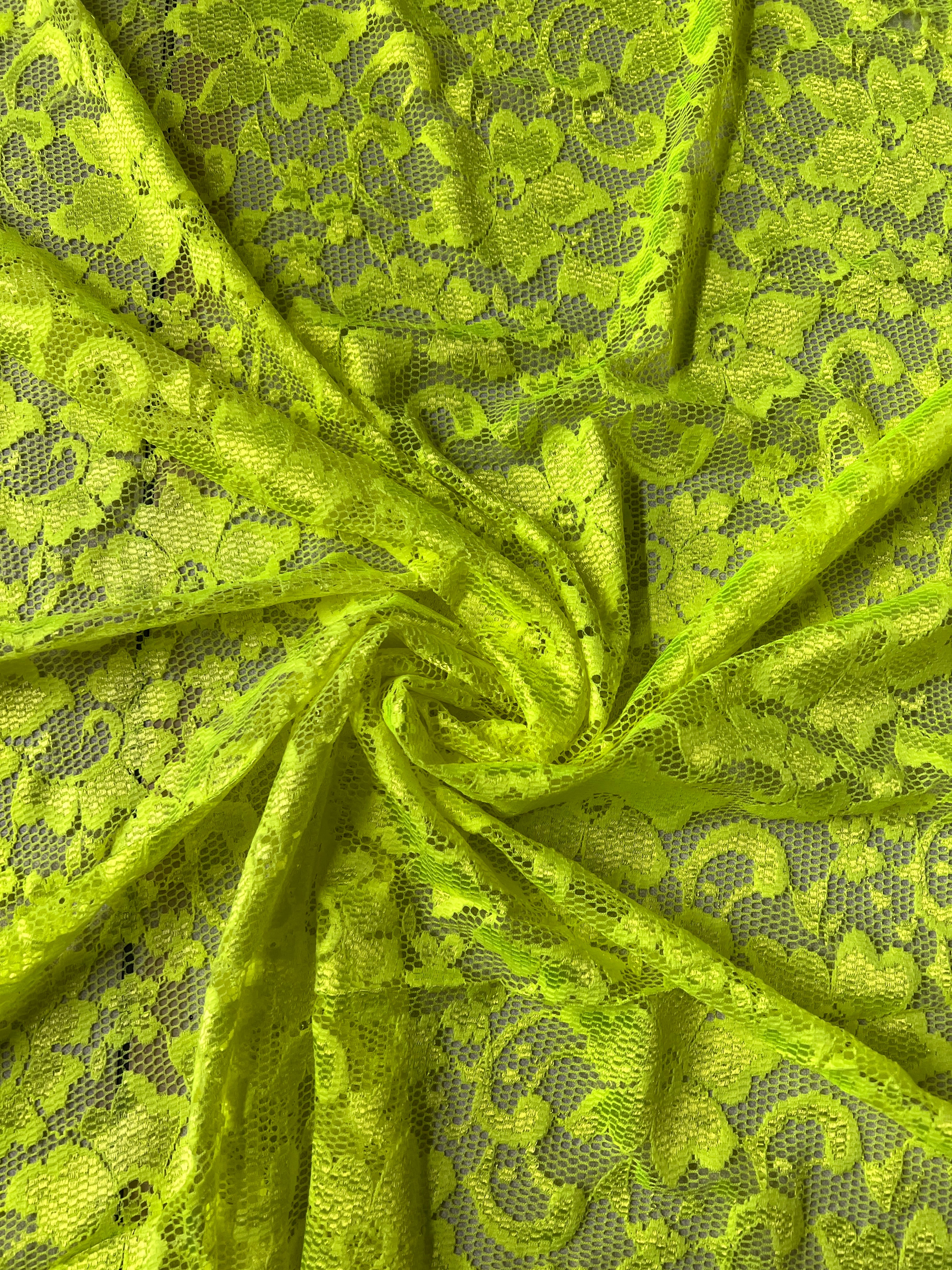 Roll of green lace fabric with a detailed pattern