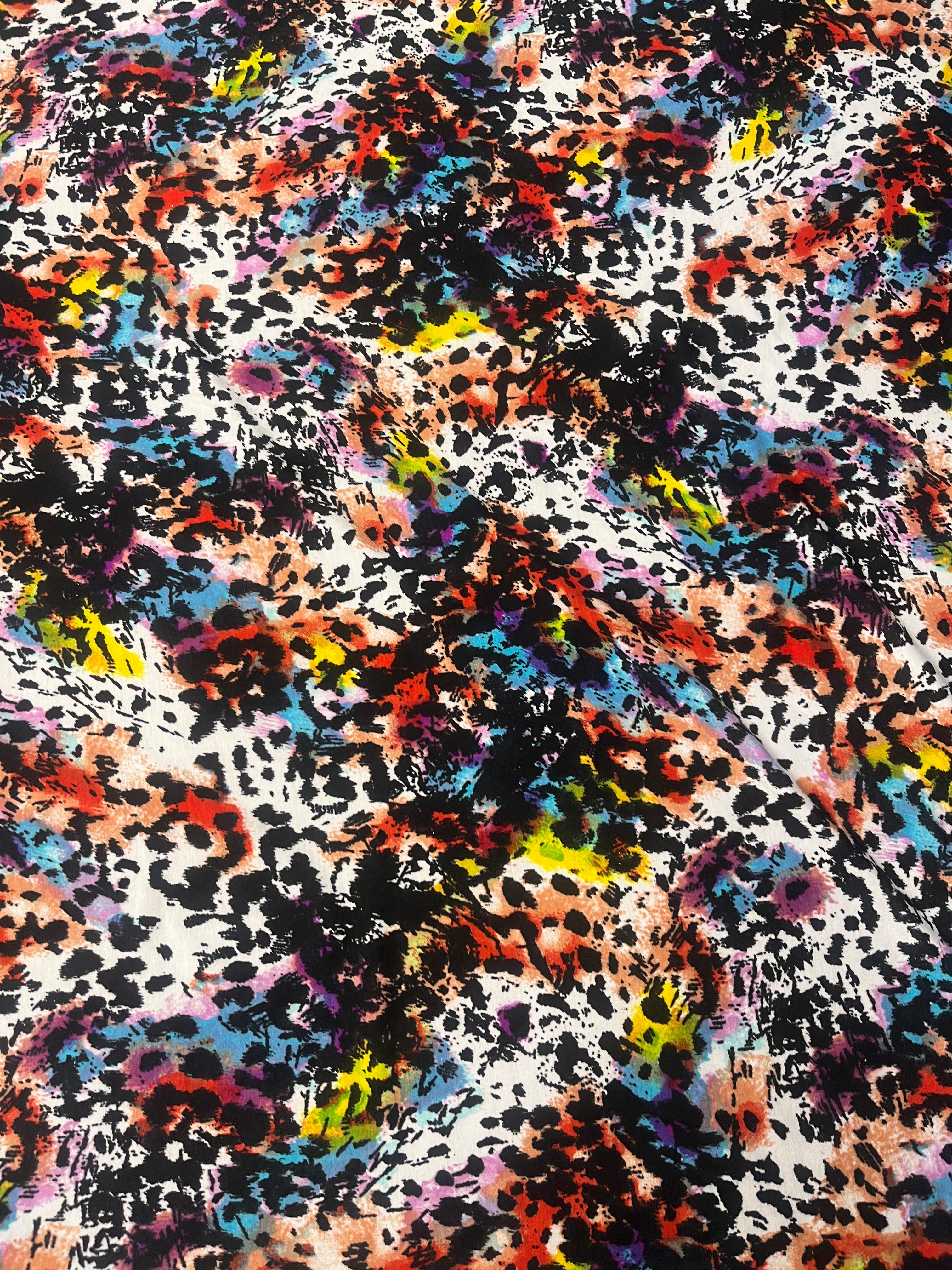 Multicolored abstract pattern resembling a leopard print on a textured fabric background