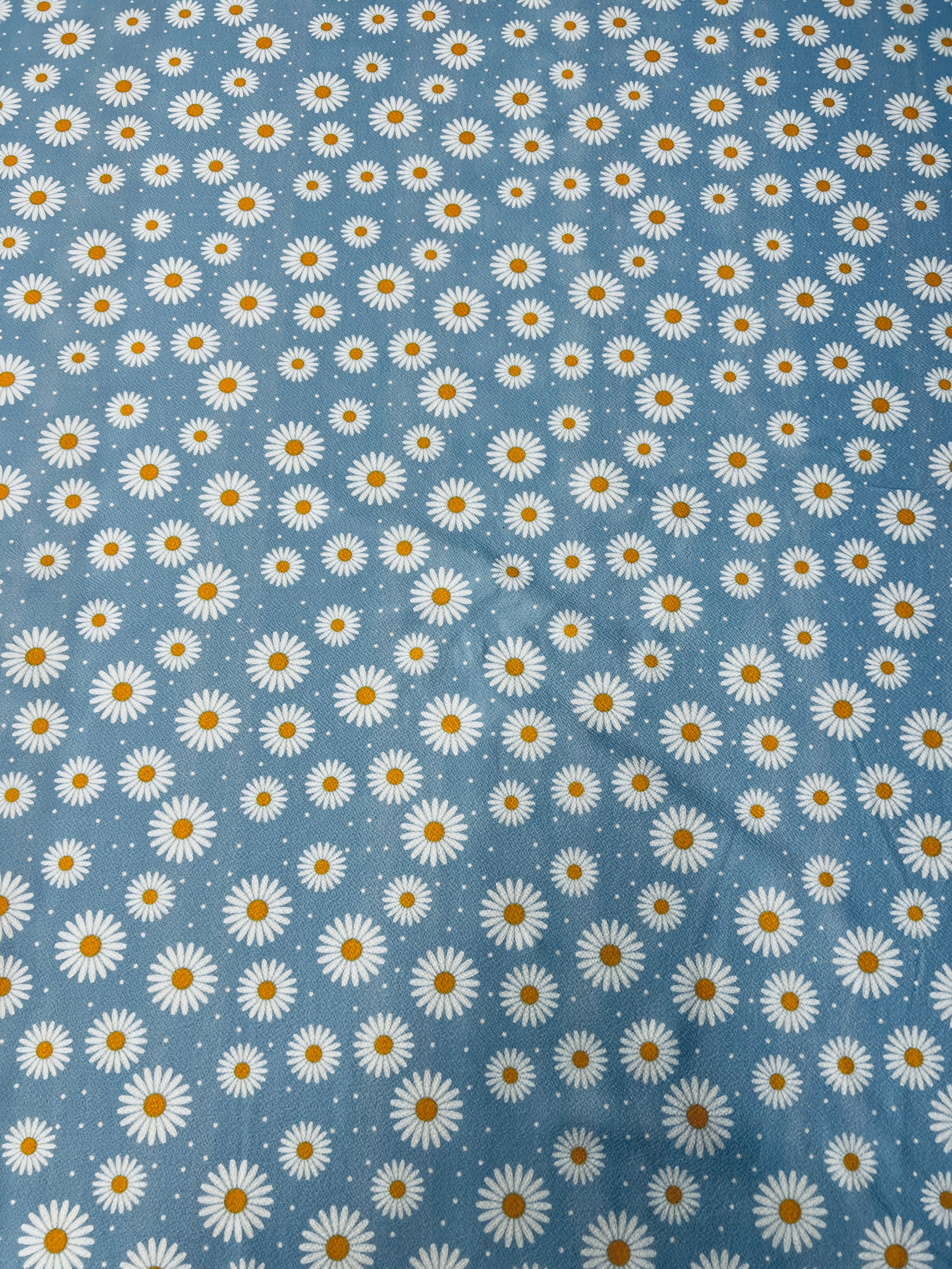 Close-up of blue daisy floral fabric texture.