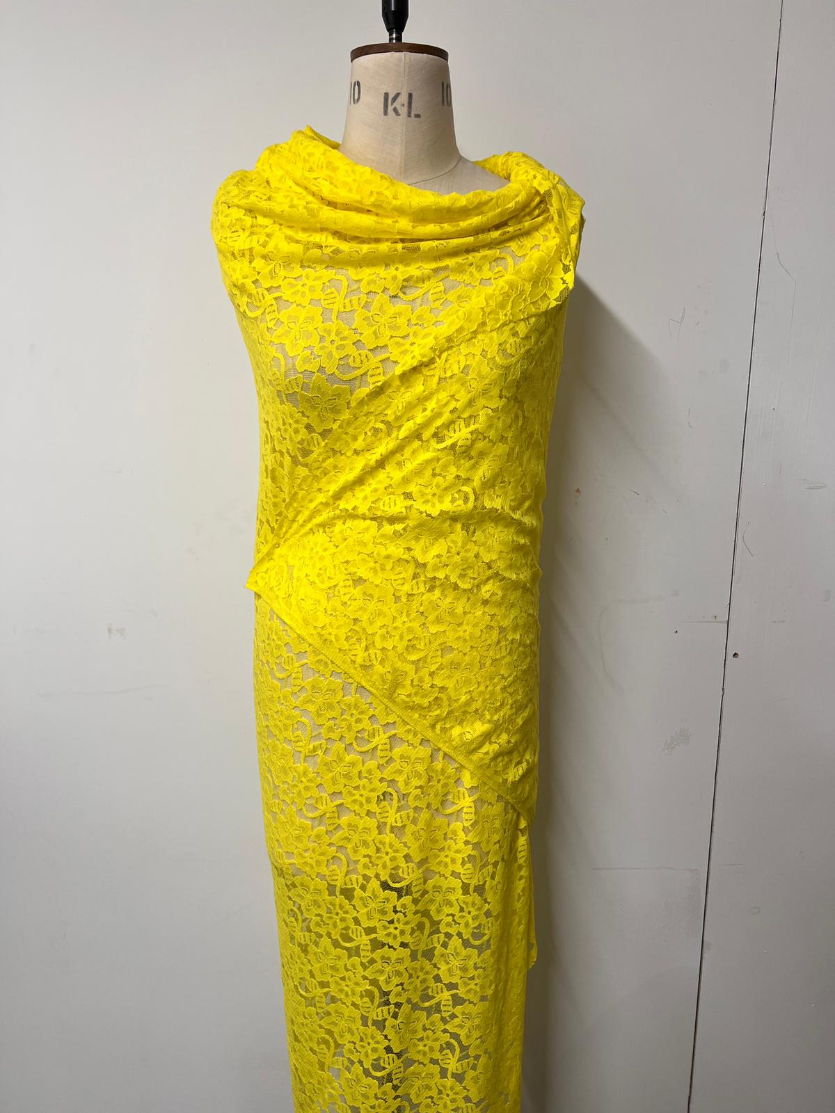Yellow lace dress on a mannequin against a plain background