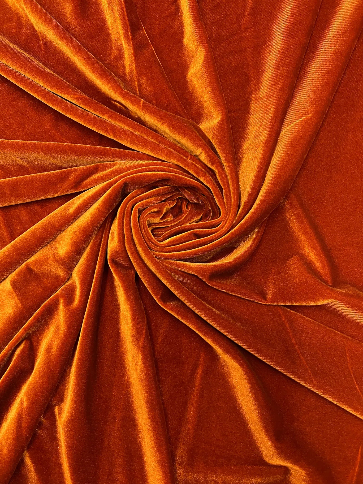 Luxurious burnt orange stretch velvet fabric with a rich sheen