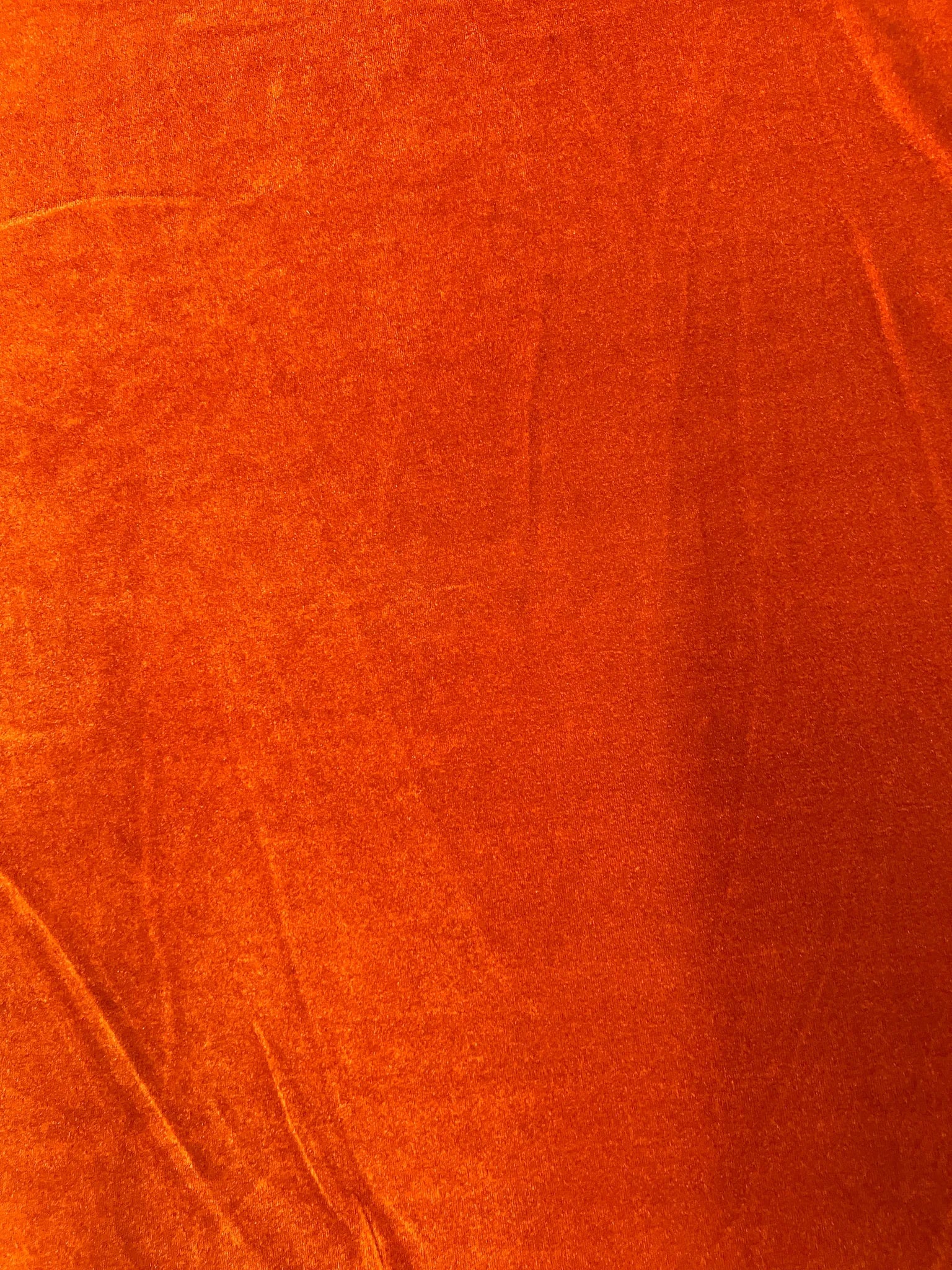 Draped burnt orange stretch velvet fabric showcasing its elegant flow