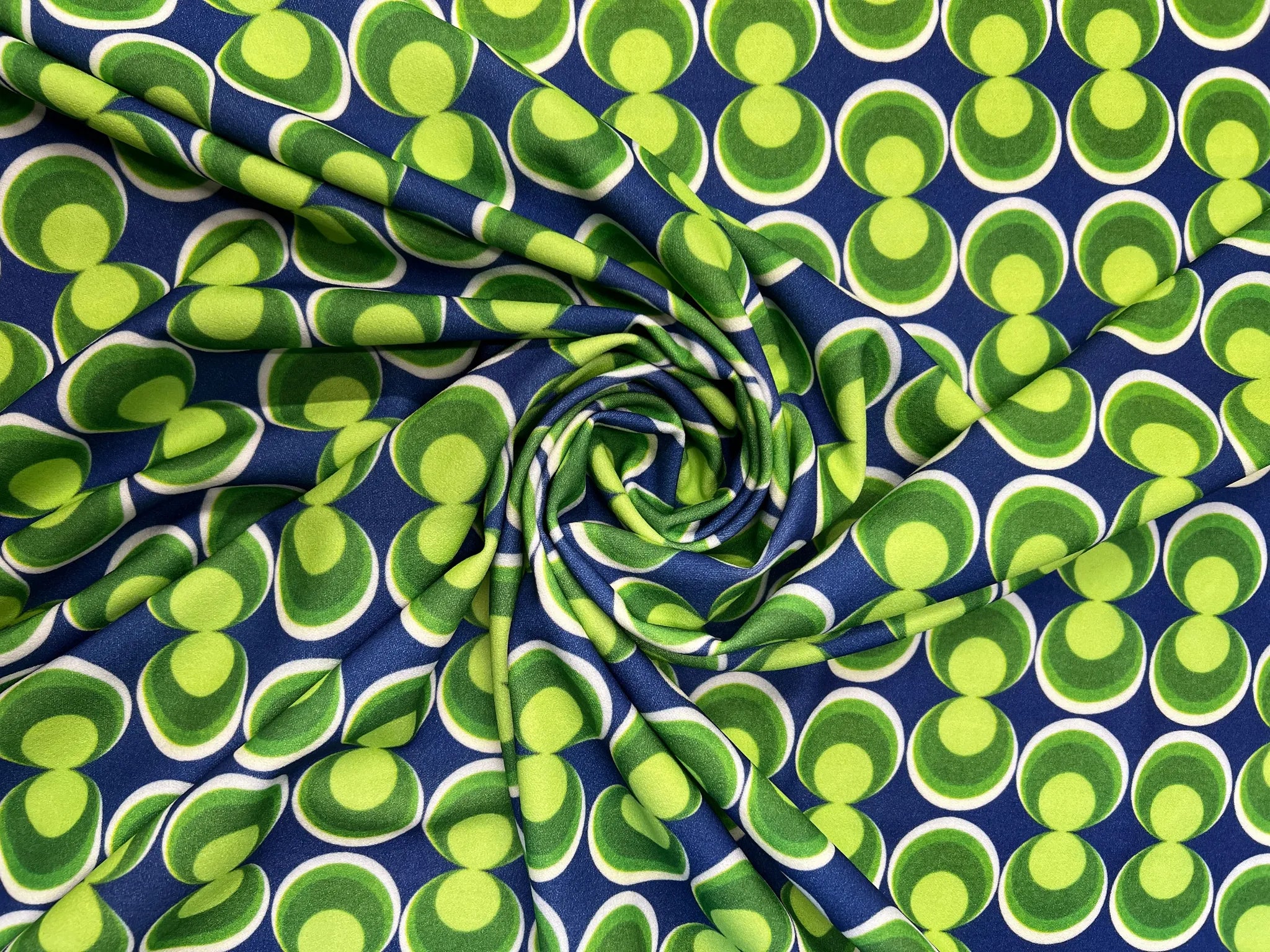 Close-up view of retro geometric blue and green scuba crepe fabric