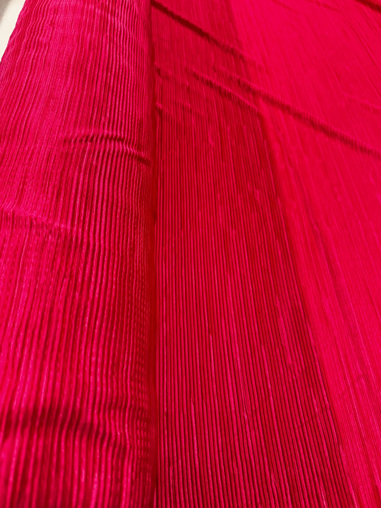 Close-up of hot pink pleated fabric showcasing texture and sheen