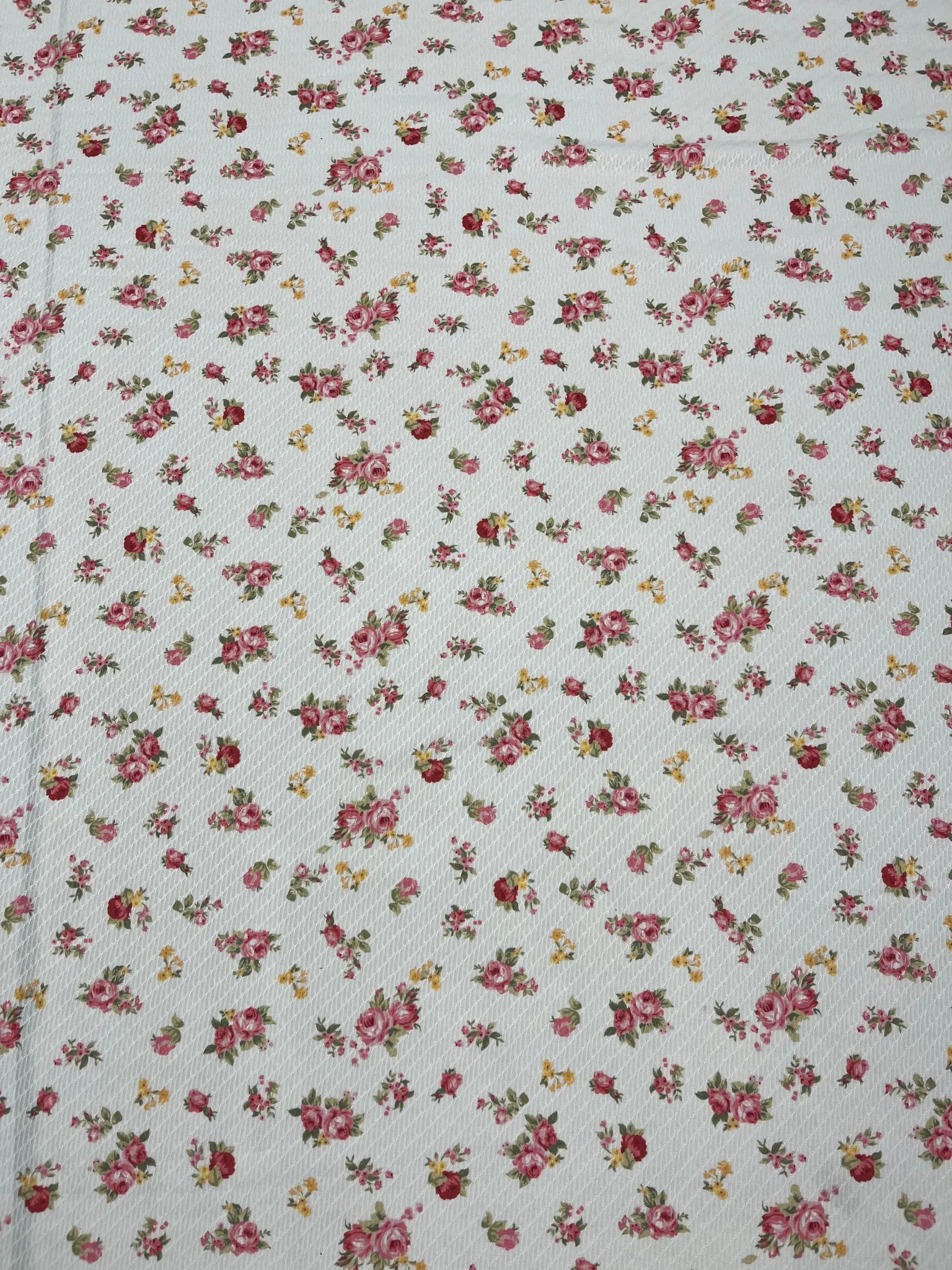 Textured white fabric featuring pink rose patterns
