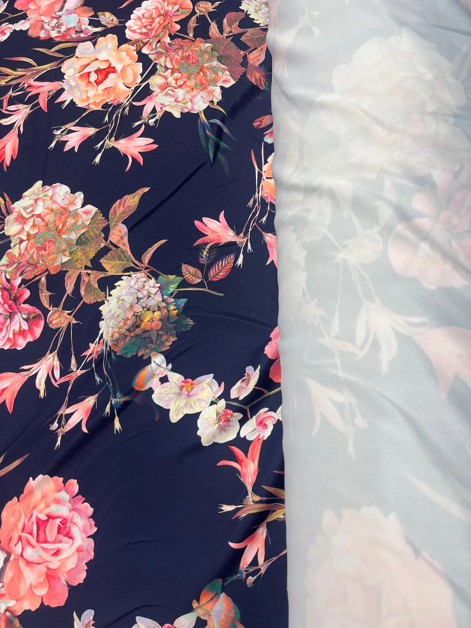 Close-up of coral and blush floral patterns on navy fabric
