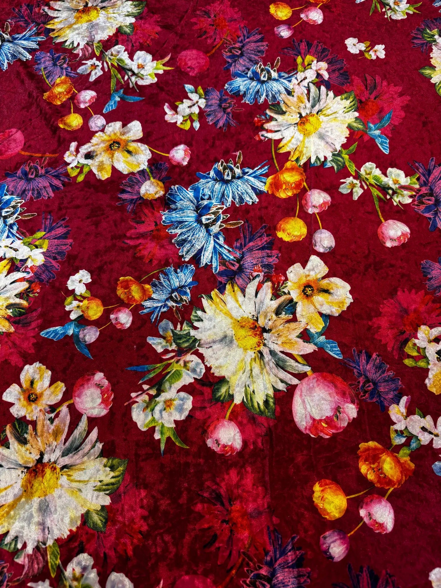 Roll of vibrant red floral crushed velvet fabric on display