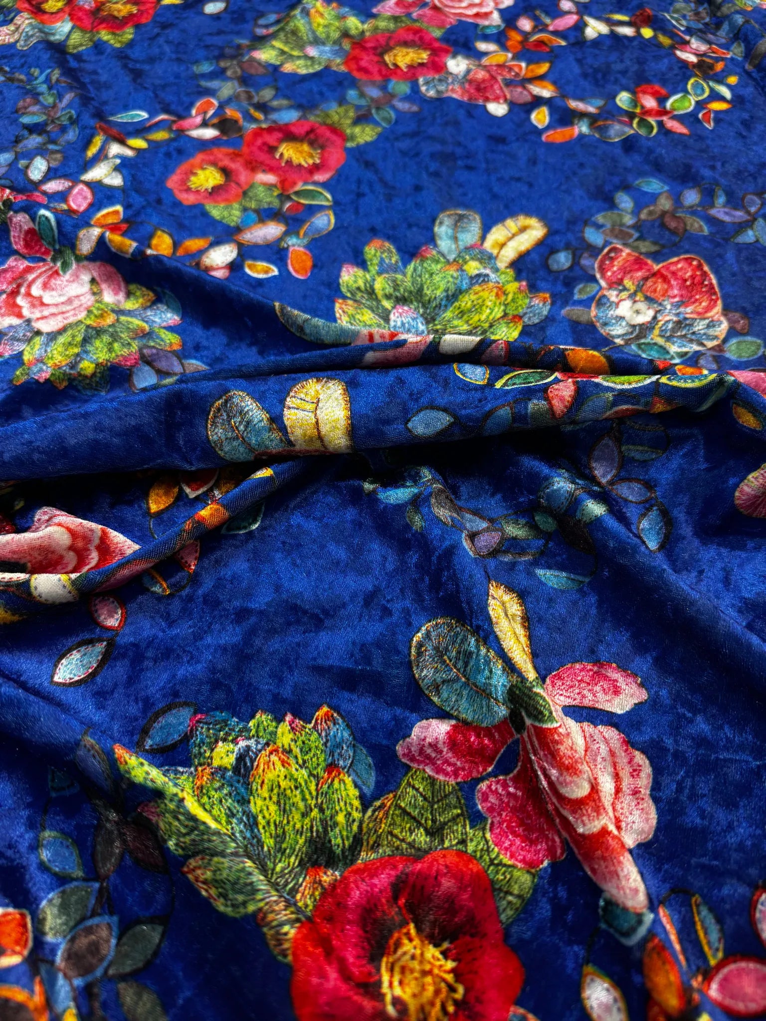 Fluid drape of royal blue velvet fabric with floral prints.