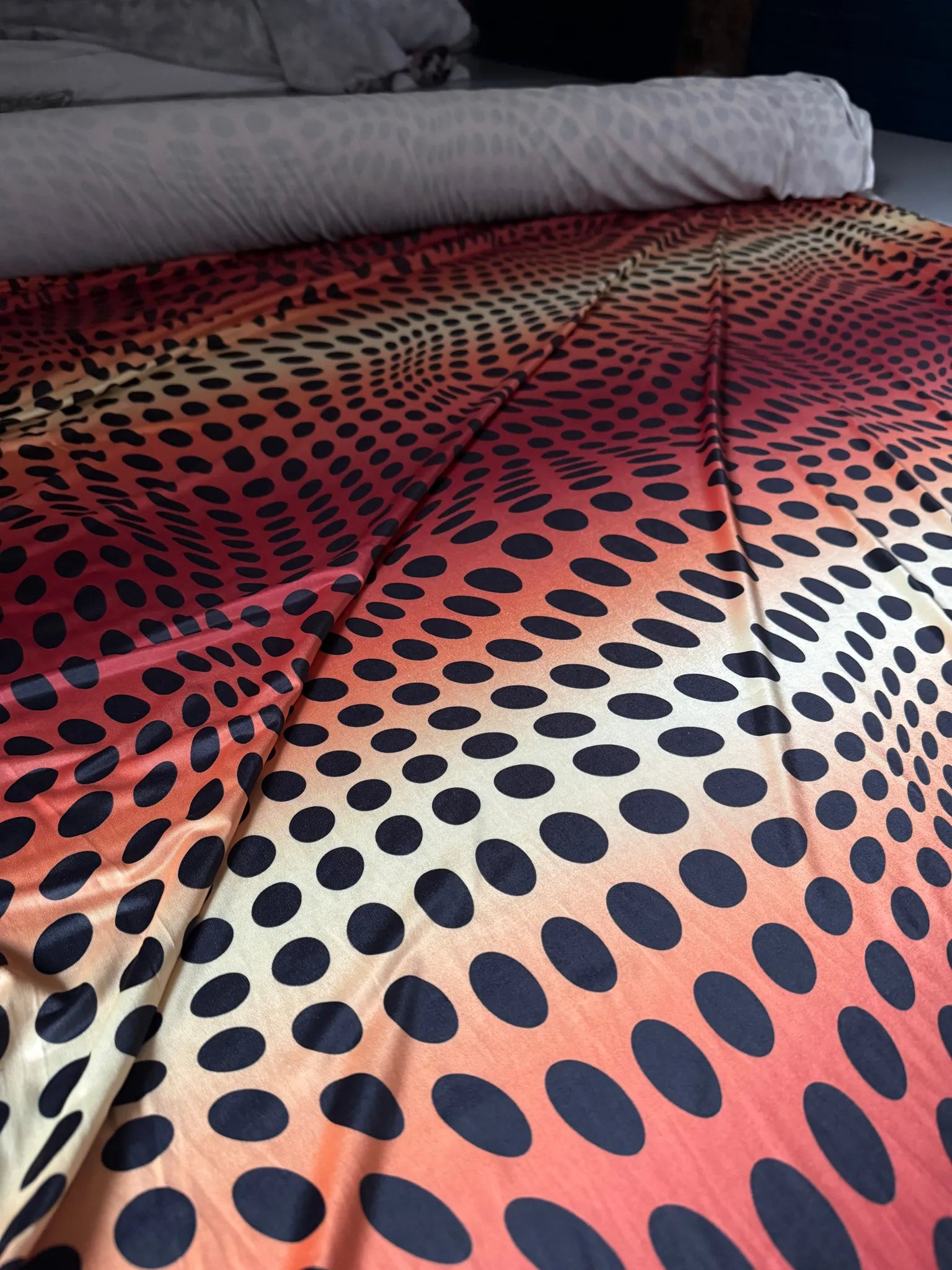 Red & Orange Sunset Ombré Polka Dot Slinky Jersey Fabric – laid flat on the cutting table
