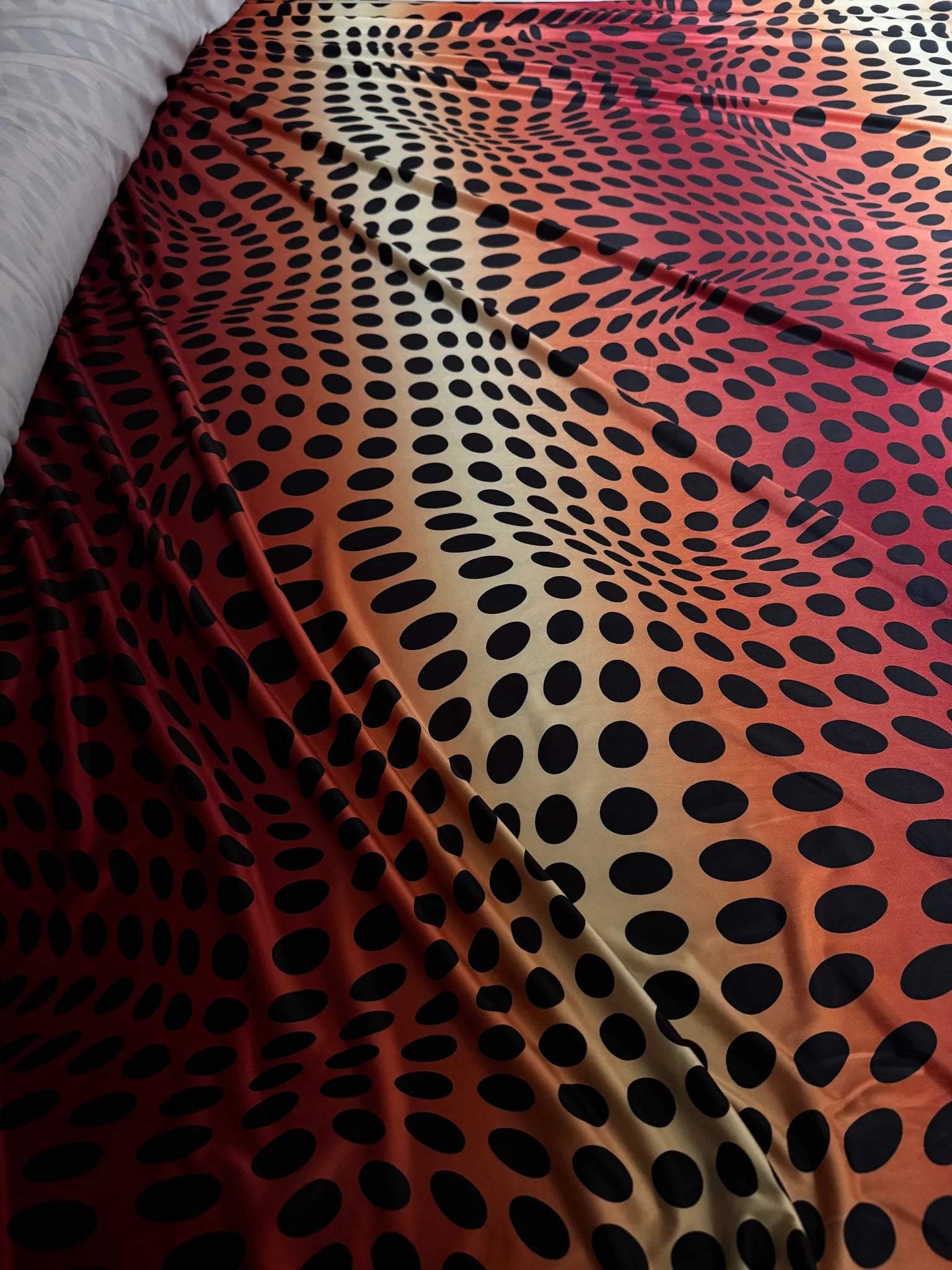 Red & Orange Sunset Ombré Polka Dot Slinky Jersey Fabric – laid flat on the cutting table