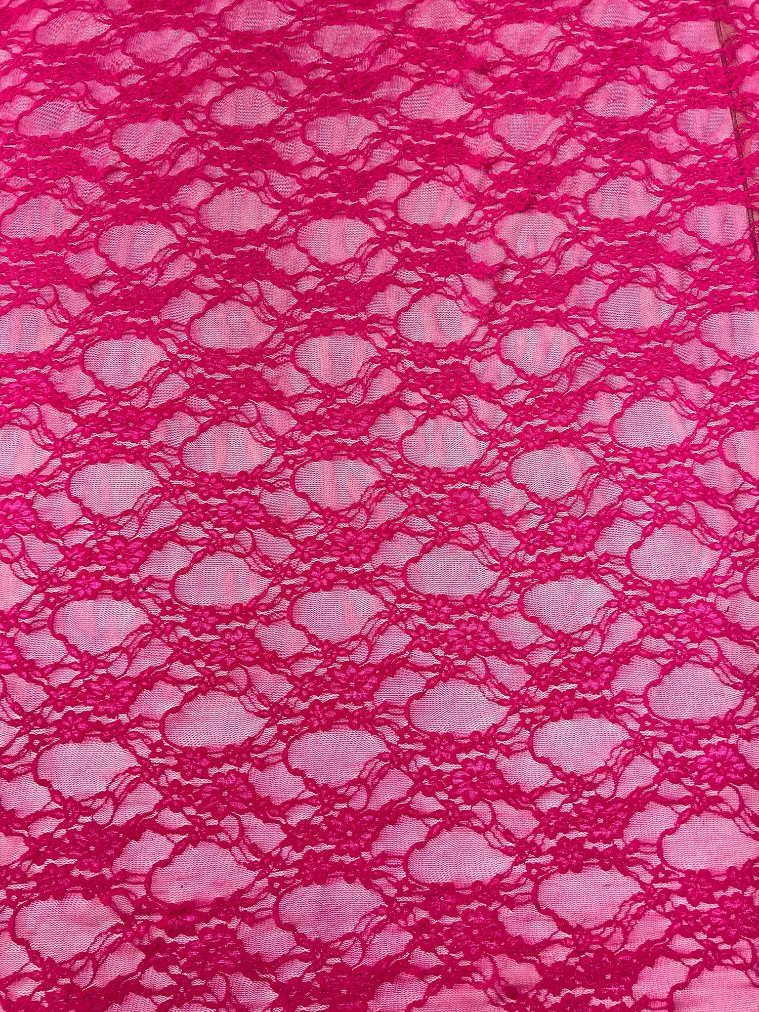 Elegant drape of hot pink floral lace fabric displayed
