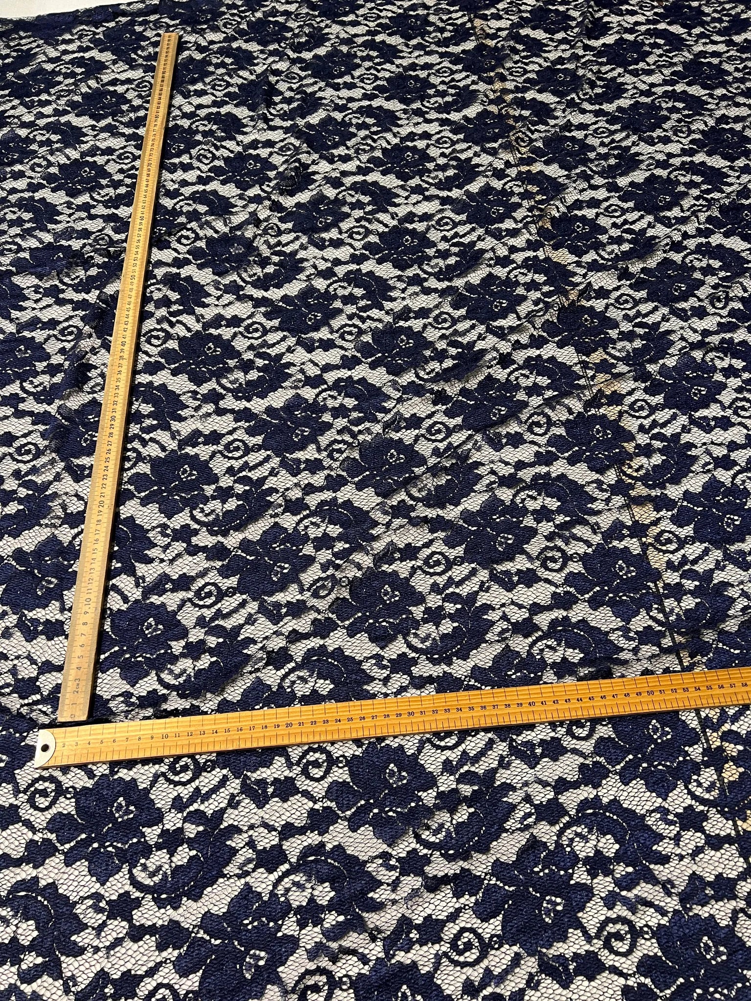 Floral patterned navy lace fabric on a white background