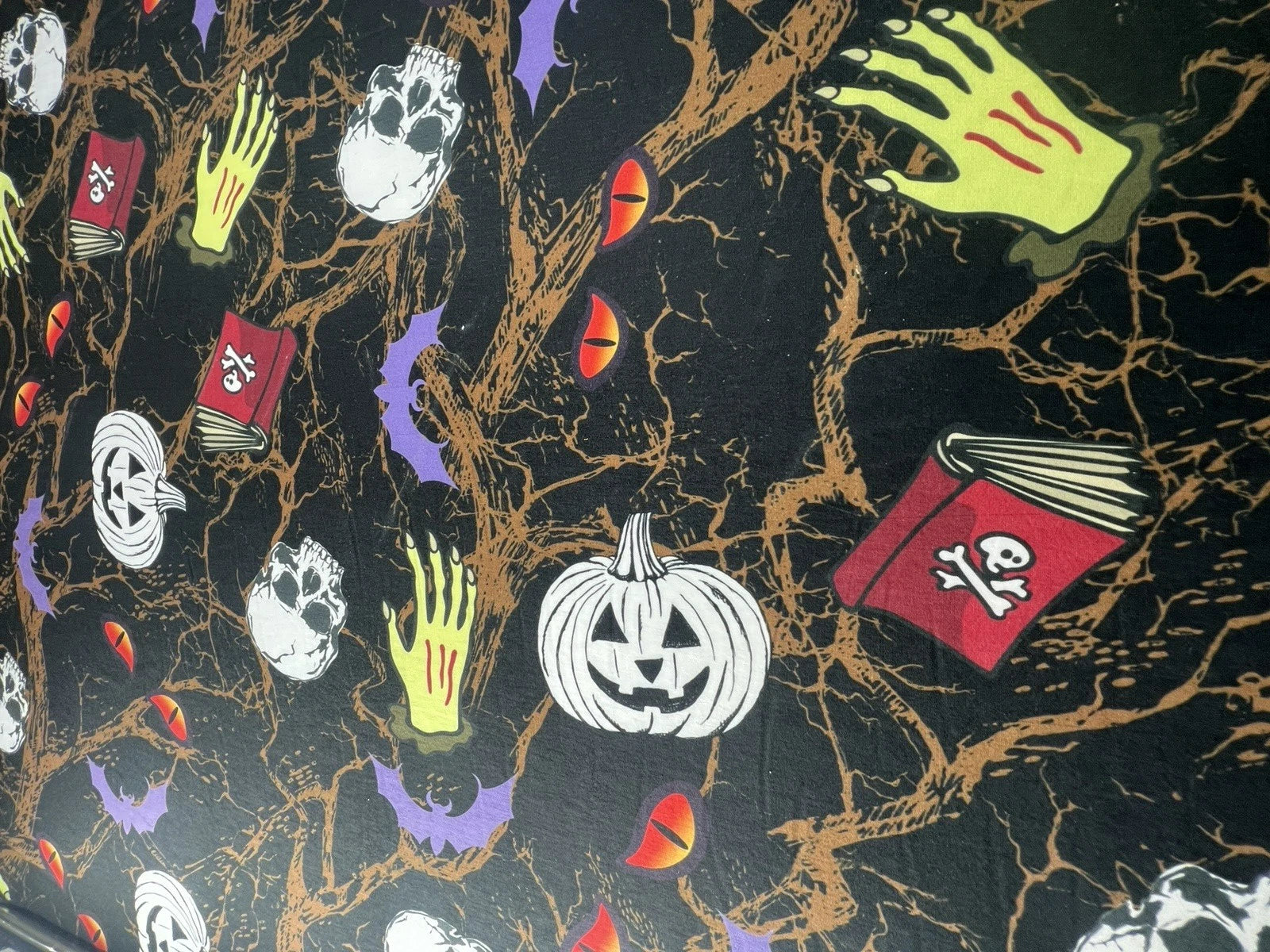 Halloween-themed fabric with pumpkins, books, and ghosts on a black background