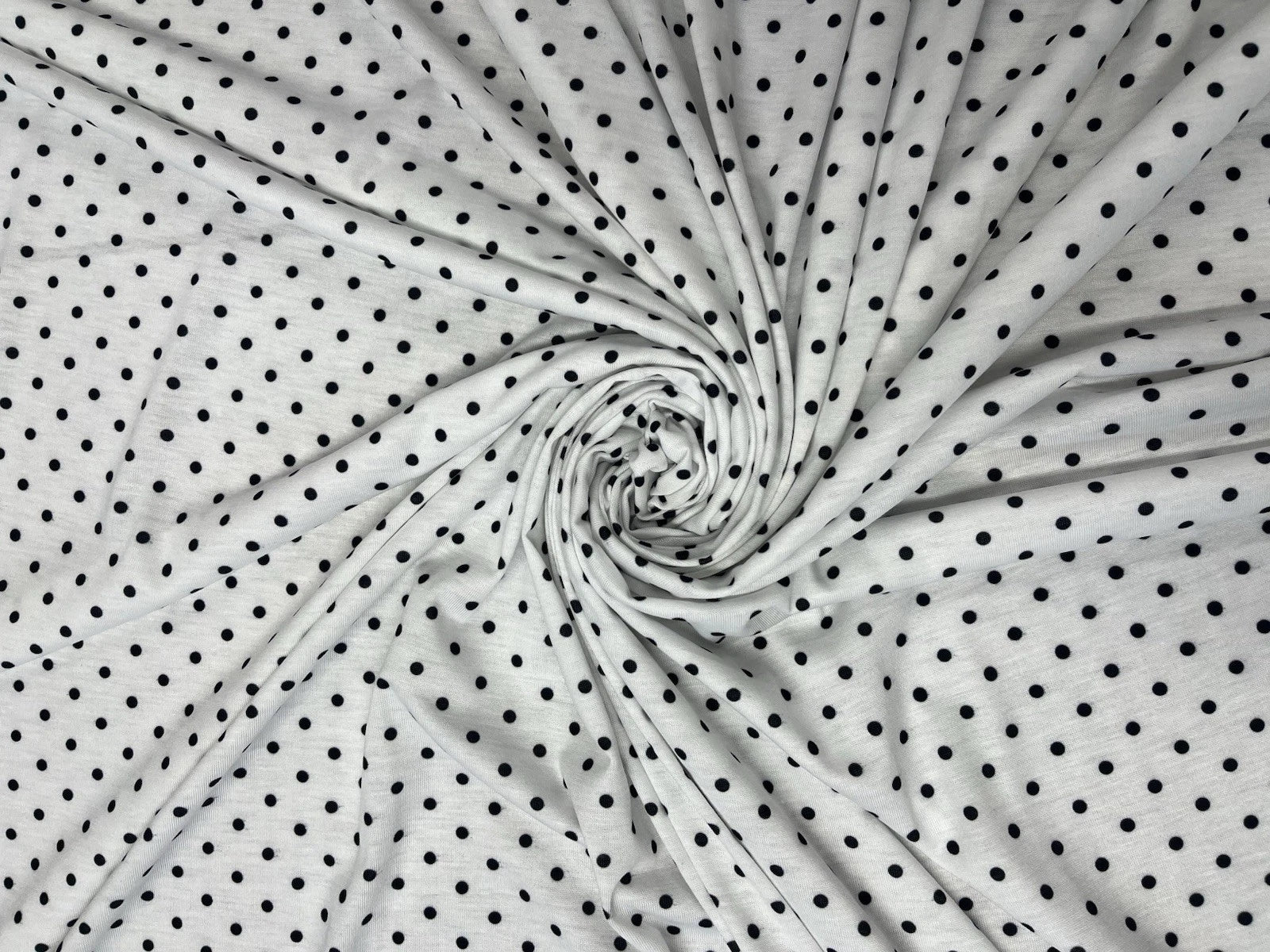 White fabric with black polka dots in a swirl pattern