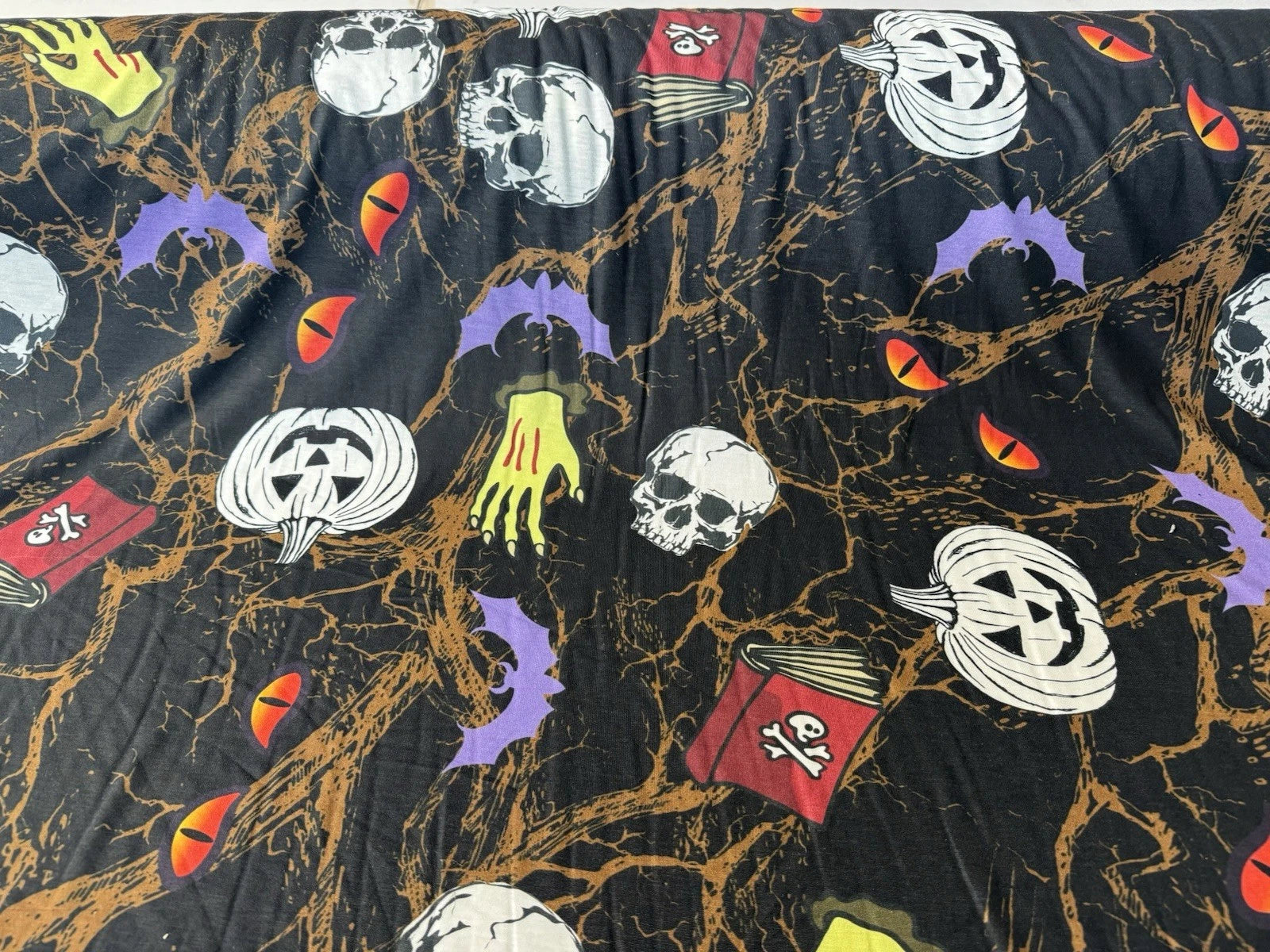 Halloween-themed fabric with pumpkins, ghosts, and bats on a black background